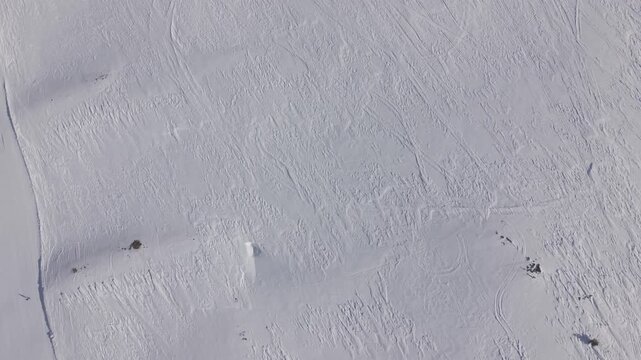 Aerial top-down backward tracking shot over a pure white snow texture background