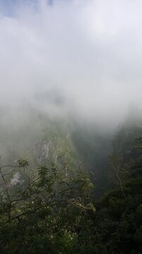 Atmospheric mountain landscape featuring steep cliffs partially covered by moving fog
