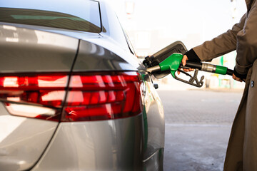 Close-up of hand refilling vehicle with gasoline. Fuel pump inserted into tank during refueling © Rabizo Anatolii