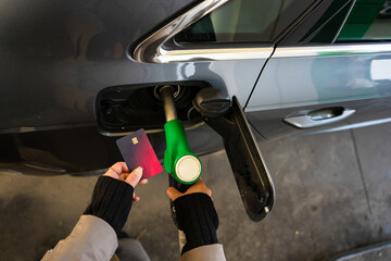 Driver using bank card at fuel pump while refilling car © Rabizo Anatolii