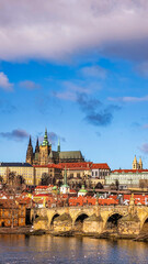 Naklejka premium Vertical view of Charles Bridge and Prague Castle over Vltava river. Famous Czech Republic landmark with Gothic Saint Vitus Cathedral and red rooftops. Mobile wallpaper and smartphone background.