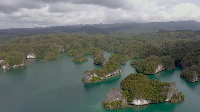 High altitude flyaway from remote tropical island with reefs and dark clouds in Raja Ampat