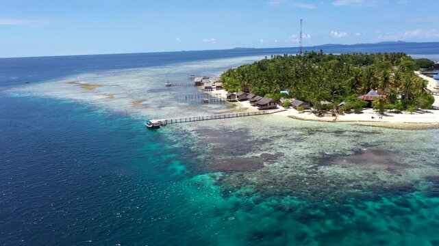 Aerial orbit of tropical paradise island with palm forest, jetties and coral reef in Raja Ampat