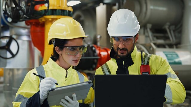 Technician inspects chiller, compressor and pipelines, recording diagnostics on tablet to ensure safe, efficient industrial cooling.
