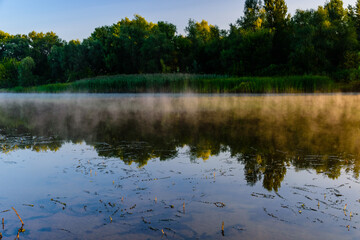 Fototapeta premium Fog above the water surface. Sunrise at river