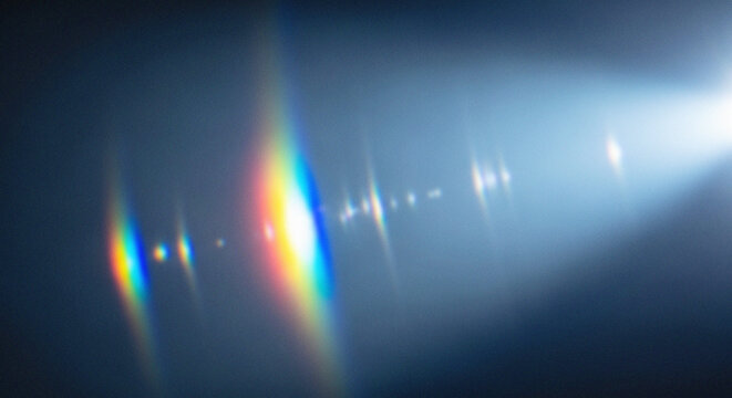 A beam of light with rainbow colors shining through a dark space with lens flares