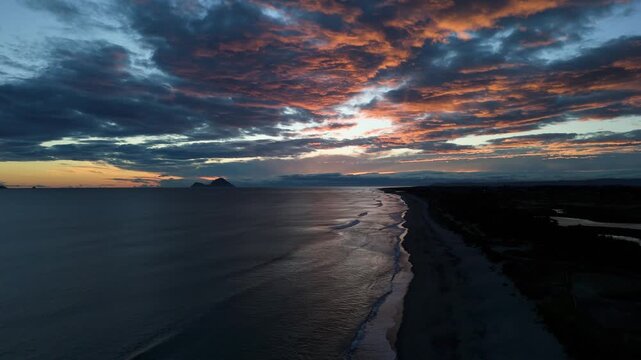 Drone aerial view of dramatic ocean coastline and sandy beach at sunset, New Zealand
