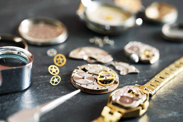Mechanism of vintage wrist watch and gears on black table, closeup