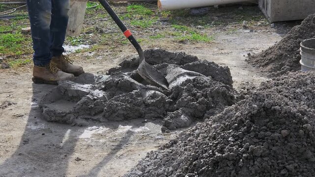 Construction worker mixing mortar with a shovel at the construction site