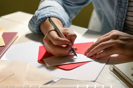Man writing letter at white wooden table indoors, closeup
