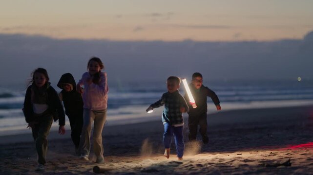 Group of children playing with a panda mascot on the beach at sunset