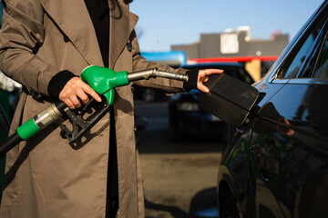 Fuel pump inserting into tank during refueling. Close-up of hand refilling vehicle with gasoline © Rabizo Anatolii