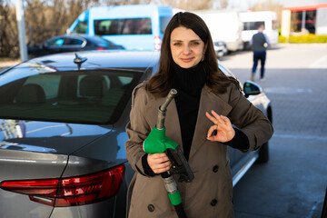Woman holding gasoline pump and showing okay sign © Rabizo Anatolii