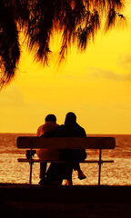 Obraz premium Silhouette seniors couple waiting for the colourfull sunset on the bench near the Indian Ocean, Mauritius, Africa