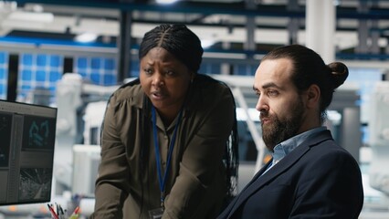 Multiethnic team of experts sharing details for the photovoltaics production line, examining...