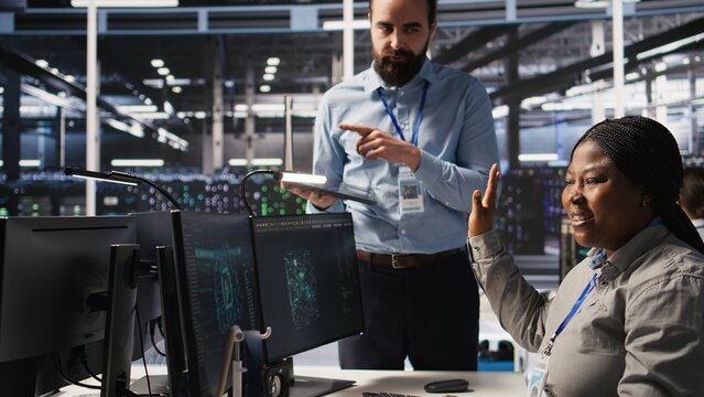 Annoyed data center employee making rude hand gesture toward colleague during workplace disagreement. Upset woman in server hub being dismissive to coworker during dispute, camera A