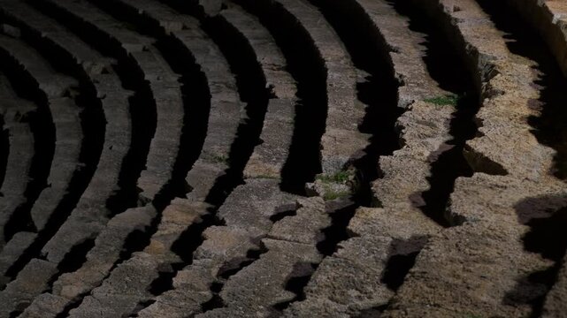 Ancient stone steps of amphitheater changing with light. Sunlight illuminates the weathered stone steps of the ancient amphitheater, revealing the textures and patterns created by time and nature