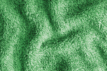 Close up, macro of crumpled green terry towel fabric with wrinkles and soft waves. Fluffy microfiber texture with dense fibers, textile, material structure, detailed cloth abstract background © katyamaximenko
