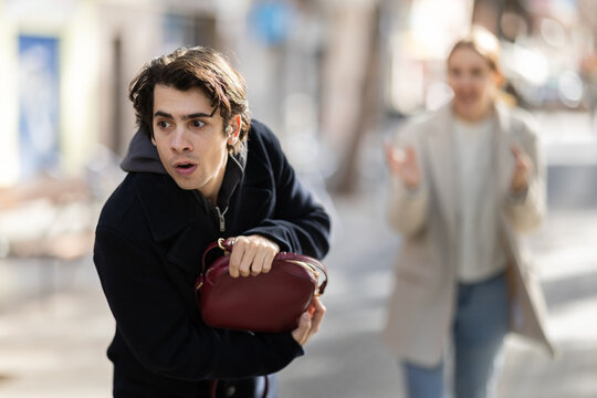 Male thief attempts to steal woman's handbag from frightened young woman
