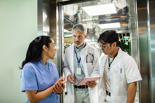 Doctors and nurse discussing patient case in hospital elevator