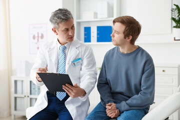 Obraz premium Urologist showing clipboard to patient on medical couch in clinic