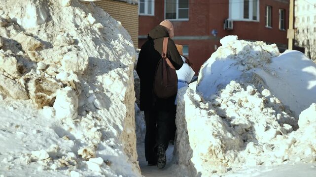 Woman walking through snowdrifts in winter city navigating urban environment
