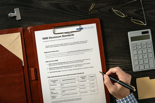 ISSB Disclosure Standards: Realistic mock-up mock placed on  with calculator, pen, sticky note. Contributor-created fictional business document for illustrative purposes.