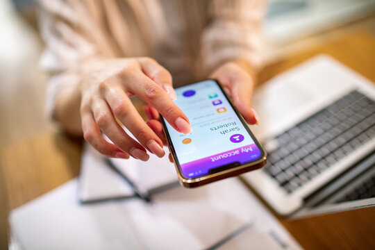 Woman using mobile banking app at home office desk