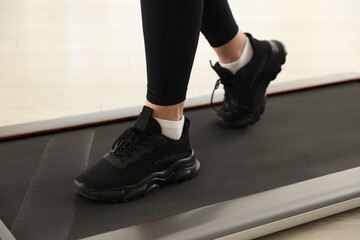 Naklejka premium Sporty woman training on treadmill at home, closeup