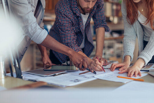 Creative team collaborating over blueprints in design studio