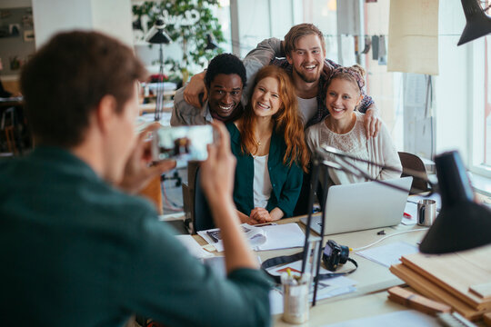 Happy coworkers posing for smartphone photo in modern office