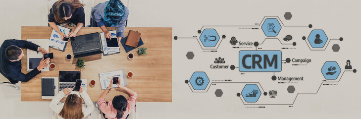 A diverse team engages in a collaborative business meeting, discussing CRM strategies and insights while utilizing laptops and documents to enhance customer management. Tessel