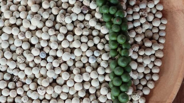 White and green peppercorns in a wooden plate.