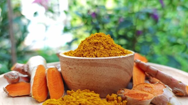 Turmeric rhizome, turmeric powder herbs in a wooden bowl.