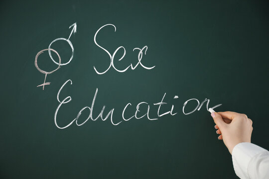 Woman writing words Sex Education on green chalkboard, closeup