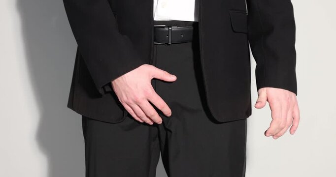 Urology. Man holding his groin and showing thumbs down on grey background, closeup