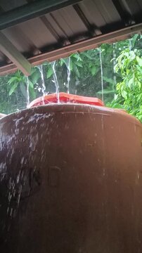 Rainwater overflowing from rooftop into large household water tank