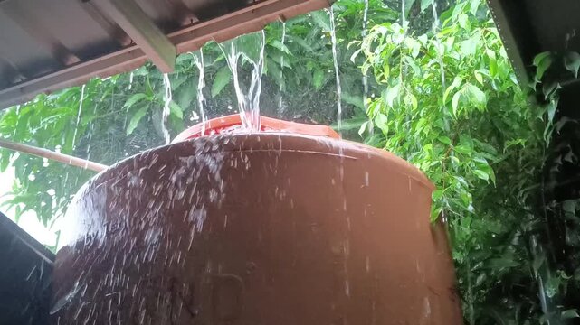 Rainwater overflowing from rooftop into large household water tank