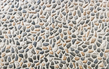 Close-up of terrazzo surface with mixed stone chips embedded in cement. Natural gray, black, and beige fragments create a decorative textured pattern background.