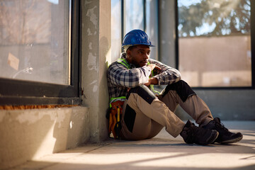 Pensive black construction worker taking break at work.