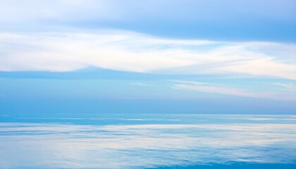 Fototapeta premium Serene ocean horizon meeting pale blue sky with wispy white clouds