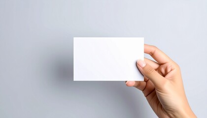 Obraz premium Hand holding blank white business card mockup against plain background space