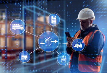Logistics management, warehouse operations. Worker in safety helmet uses smartphone while...