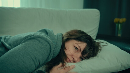 Woman resting her head on pillow looking thoughtful on couch, depression, offended woman