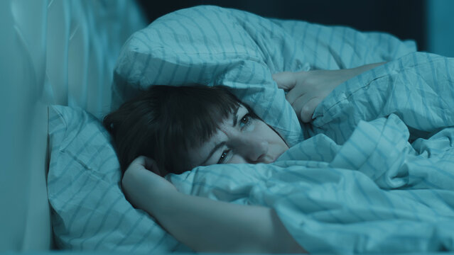 Woman Struggling with Insomnia in Bed at Night Covering Ears wit, noisy neighbors are preventing me from sleeping
