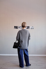Vertical shot of middle aged Caucasian woman standing with back to camera observing black and white...