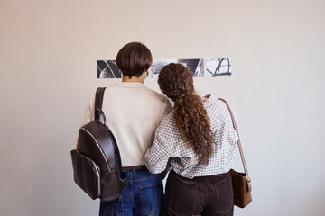 Back view of Caucasian young adult man and woman standing close together observing black and white...