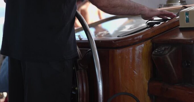 Ship captain at helm of modern pirate wooden ship - close up on helm