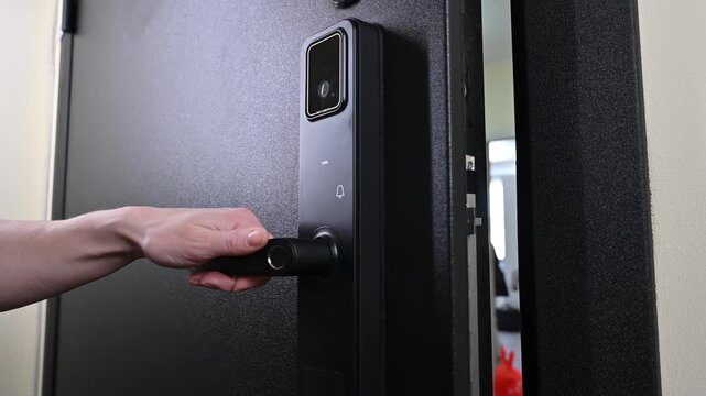 A woman opens a modern smart door lock using a contactless key.