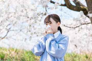 Woman blowing nose with tissue under cherry...